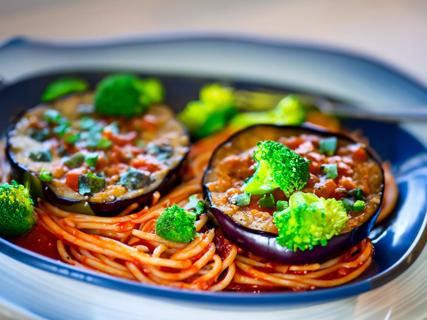 Cooked eggplant halves over marinara pasta and cooked broccolini