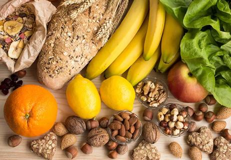 Counter filled with foods like granola, bananas, lemons, nuts, oranges and greens