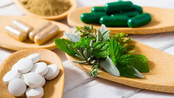 Natural antibiotics, pills and herbs, displayed on bamboo spoons on wooden table.