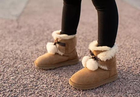 Person standing on road wearing sheepskin boots.