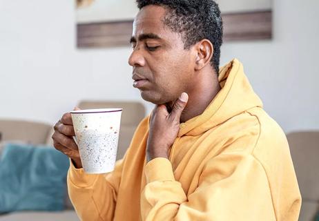 Person with sore throat drinking warm beverage before exercising.
