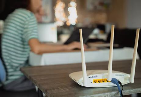 A woman is working at home using a modem router, connecting the Internet to her laptop.
