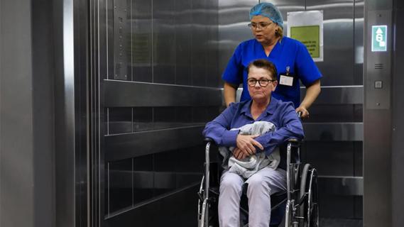 woman in wheelchair being wheeled into or out of an elevator