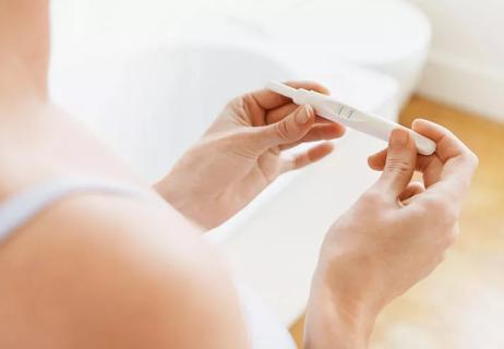 Closeup of woman in bathroom checking pregnancy test.