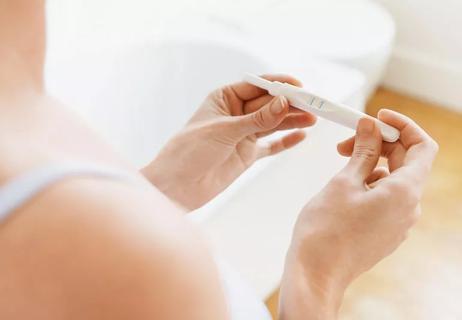 Closeup of person in bathroom checking pregnancy test.