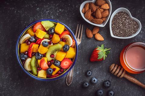 Bowl of assorted fruit and bowls of nuts and seeds