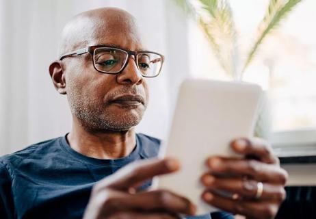elderly man with glasses reading on iPad