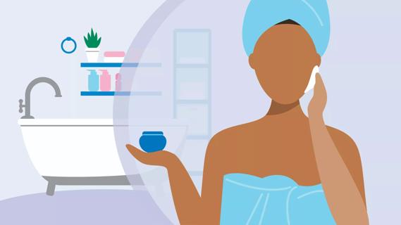 Person in towel in front of bathtub, with shelves of lotions, holding jar of moisturizer, applying to face