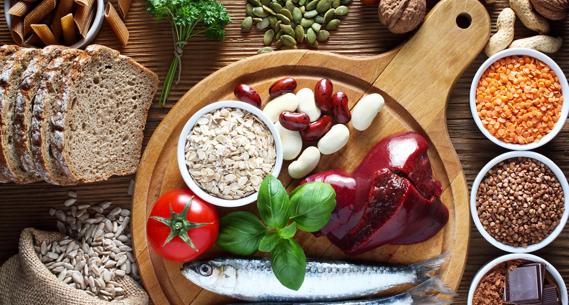 An array of copper-rich foods on wooden board, inlcuding liver, sardines, legumes and seeds