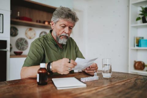 Person checking medication information, sitting at kitchen table