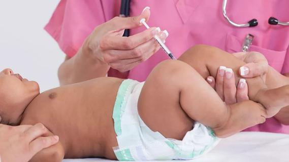 Baby receiving a shot in their leg by healthcare worker in pink