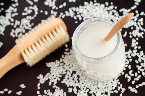 jar of rice water and brush, with rice scattered around table