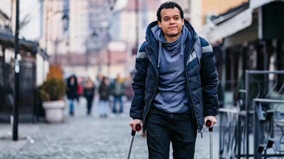 young man using walking canes on a city street