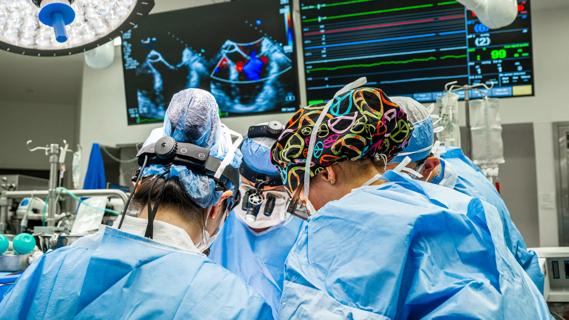 surgical team operating below monitors in an operating room