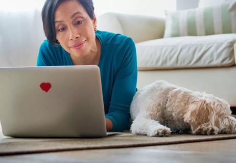 woman relaxing with dog while looking at laptop decorated with a heart