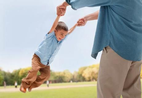 Father swinging child by arms