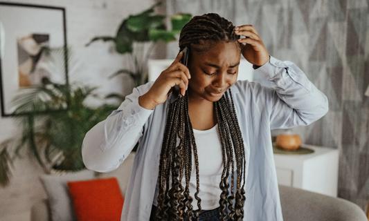 Person on their cell phone at home, upset, crying
