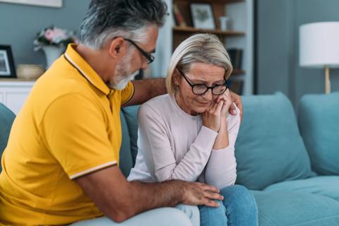 Man comforts upset woman sitting on couch
