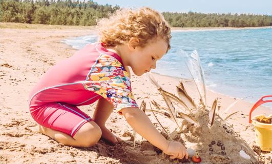 Child dressed in UPF clothing while playing at beach