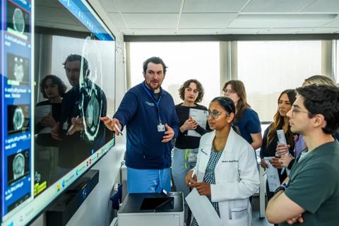 medical students gathered around a large monitor showing a brain image