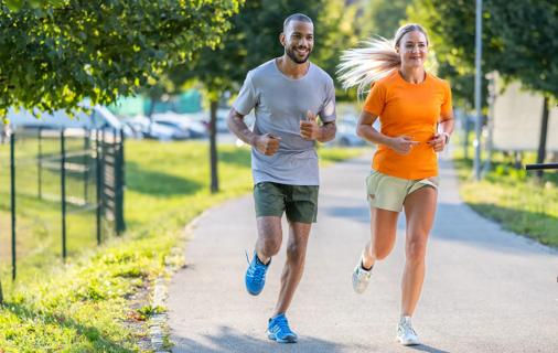 Two people jogging outside on a paved path