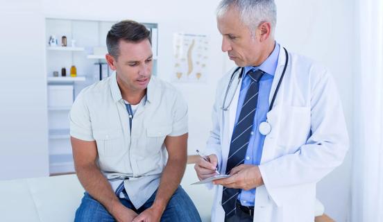 Male patient sitting on exam table talking with healthcare provider