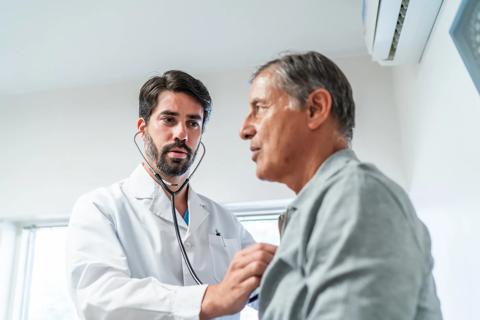 Healthcare provider using stethoscope to listen to patient's heart
