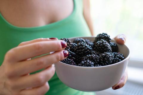 Person holding bowl full of blackberries