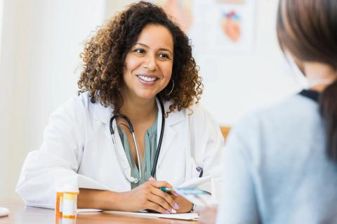 Healthcare provider talking to patient, with medication bottles nearby
