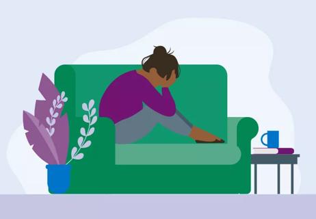 Person with chronic migrain holding head while sitting on couch.