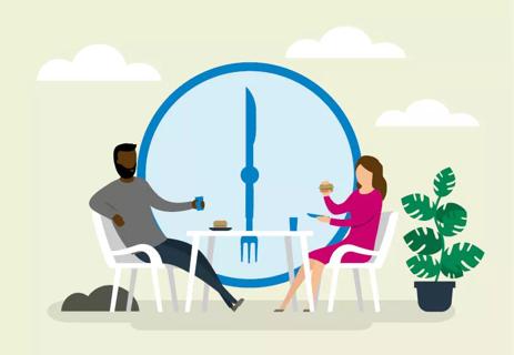 people eating dinner at table with clock in background