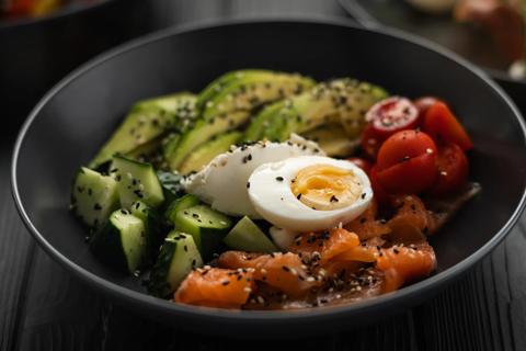 Black bowl of grains, salmon, vegetables and boiled egg