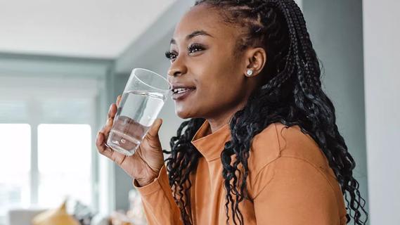 Female drinking large glass of water at home.