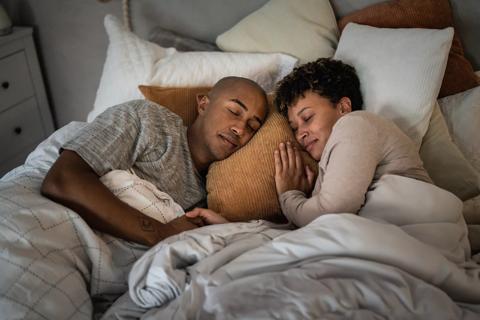 Happy couple sleeping in bed together, holding hands