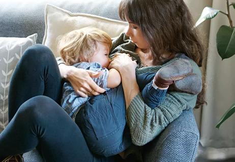 Parent breastfeeding older baby while relaxing on couch.