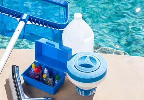 pool chemicals and testing kit sitting next to a pool