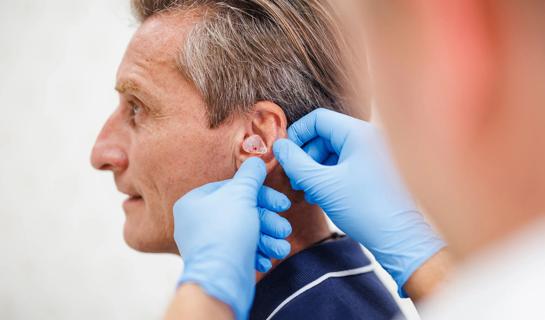 A healthcare provider fitting a patient with a hearing aid
