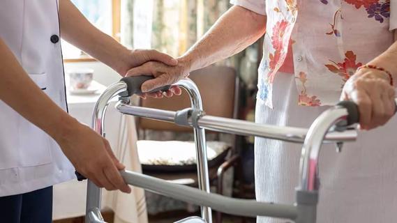 close up of caregiver's hands helping elderly person using a walker
