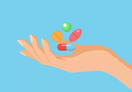 An illustration of a person's hand holding pills of different shapes and colors