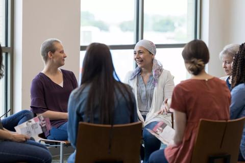 Group of women sitting in chairs in circle, some holding brochures, at cancer support group