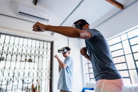 Two people wearing virtual reality gaming masks, exercising to what they see