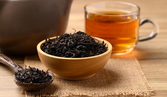 Bowl and spoonful of black tea, with glass mug of tea near