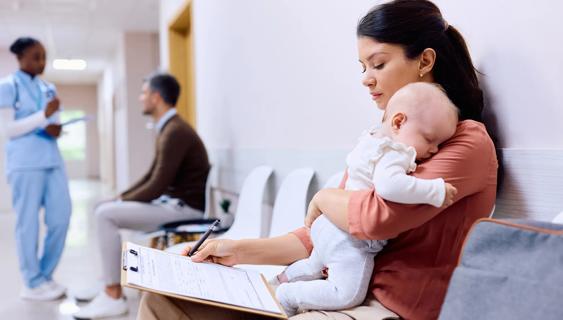 Parent at hospital holding their baby, filling out paperwork