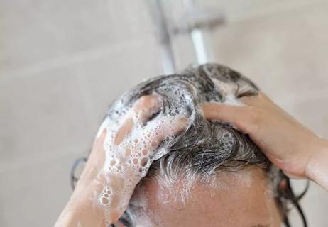 person shampooing hair in shower