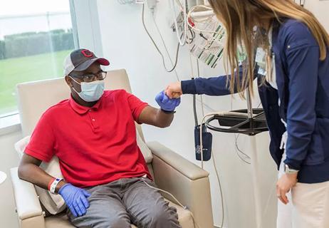 teen with cancer fist bumps with nurse in infusion unit