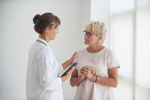 Healthcare provider speaking with older woman in medical setting