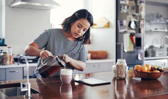 Person pouring coffee from a French press in their kitchen