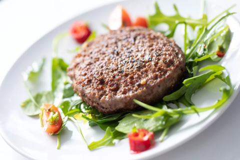 Turkey burger with cilantro, scallions and ginger on be of mixed greens