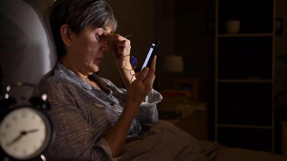 Older woman awake in bed in the middle of the night looking a smartphone