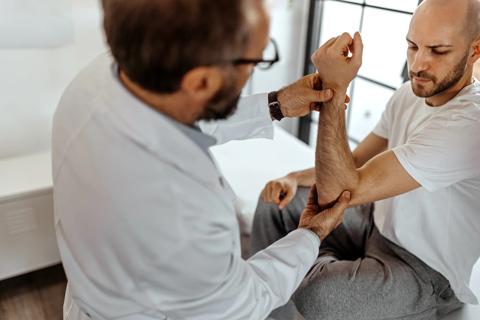 Physician examining patient's elbow